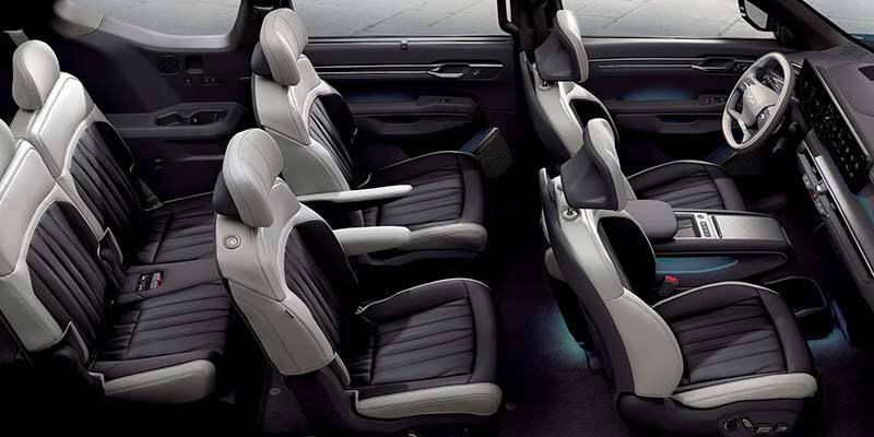 A high-angle view of a modern SUV interior featuring three rows of premium two-tone seats with dark gray ribbed centers and light gray trim.