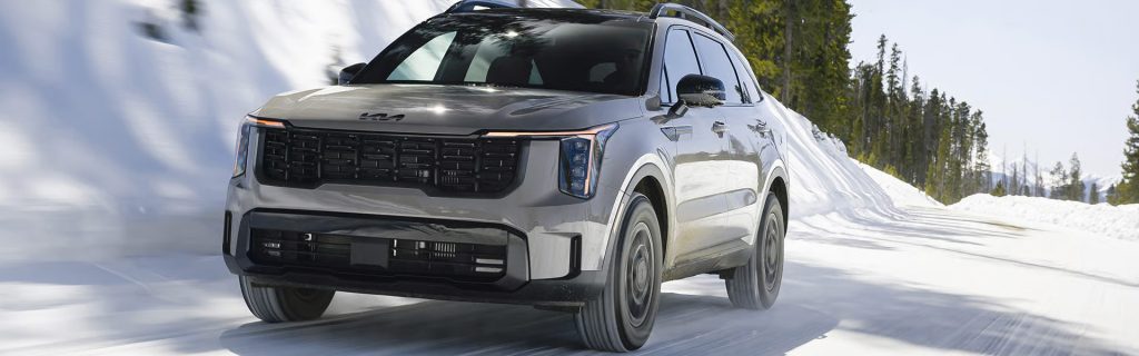 2026 Kia Sorento SUV driving on a snow-covered road with a modern gray exterior and winter mountain scenery in the background.