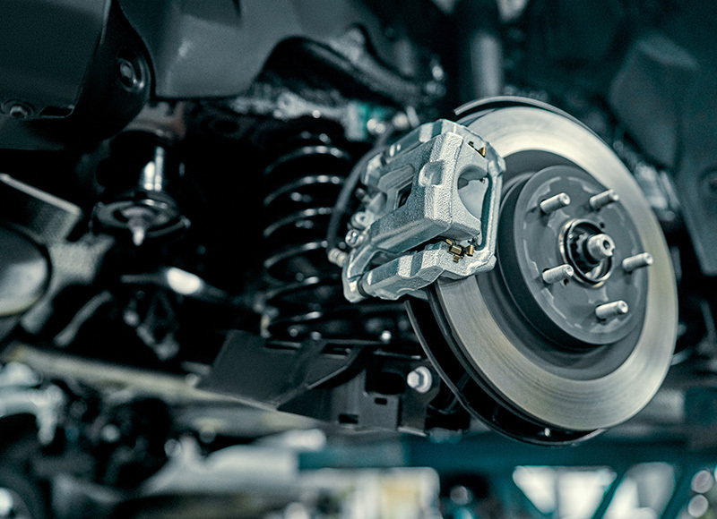 Close-up of a vehicle brake rotor and caliper assembly during suspension or brake system service.